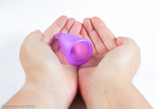 Studio shot of an isolated woman hands holding a menstrual cup, on white background.